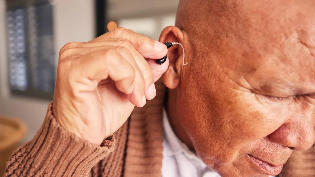 Oreille d'aide auditive et un homme âgé handicapé dans sa maison en gros plan pour écouter du bruit ou du volume Soins de santé médicaux ou sourds avec un homme mûr dans sa maison de retraite pour le bien-être