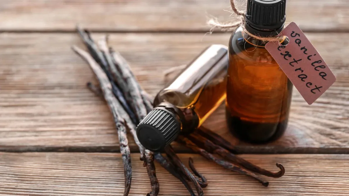 Bouteilles avec extrait de vanille et bâtons sur fond de bois