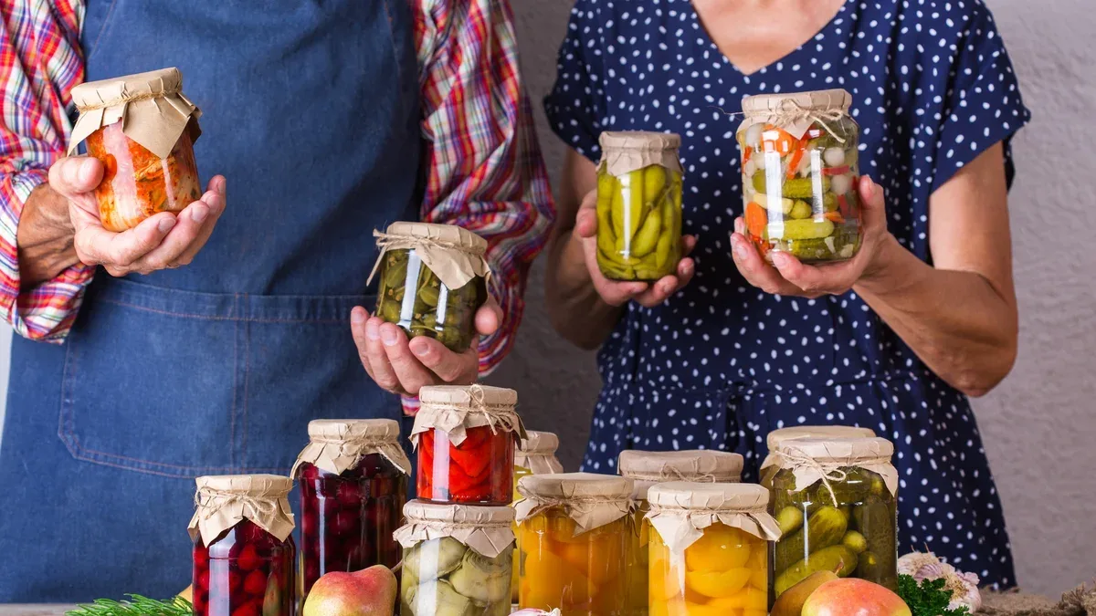 Heureux seniors tenant dans les mains des bocaux avec des aliments conservés et fermentés faits maison, marinés et marinés. Préservation des récoltes, temps en famille