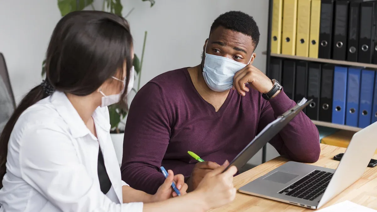 Deux personnes au bureau travaillant ensemble pendant une pandémie avec des masques médicaux