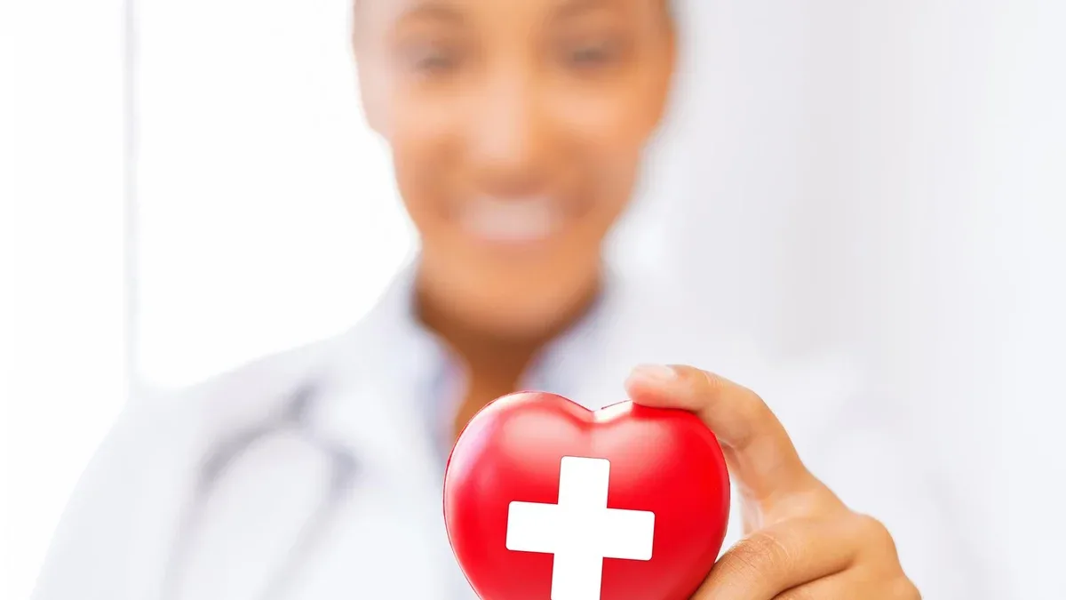 concept de soins de santé et de médecine - femme médecin afro-américaine tenant le coeur avec le symbole de la croix rouge