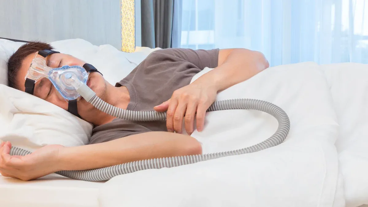 Un homme avec un masque d'oxygène dormant sur un lit à l'hôpital