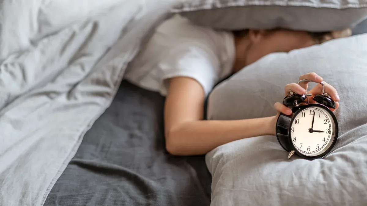 Femme, insomnie, mensonge, lit, tête, sous, oreiller, essayer, dormir Insomnie et problèmes de sommeil. Concept de détente et de sommeil. Se sent somnolent et fatigué.