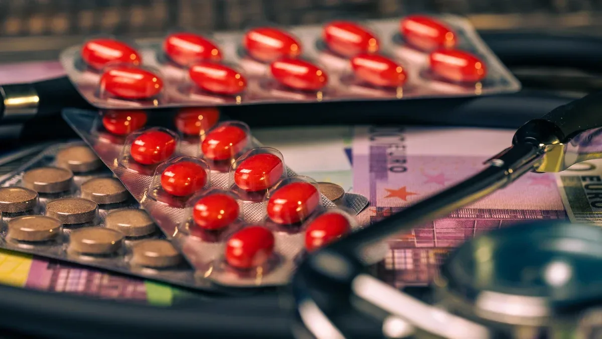 Une paire de pilules rouges sont sur une table à côté d'un stéthoscope.