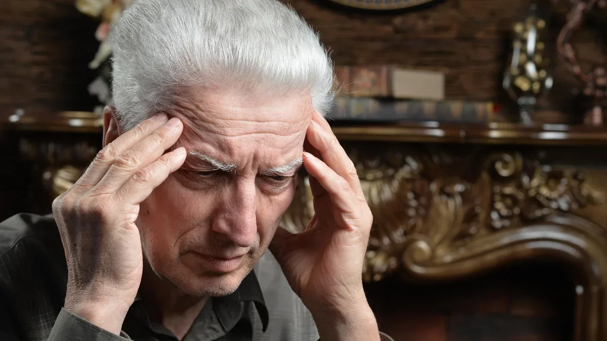 Portrait d'un homme âgé avec mal de tête tenant la main sur la tête