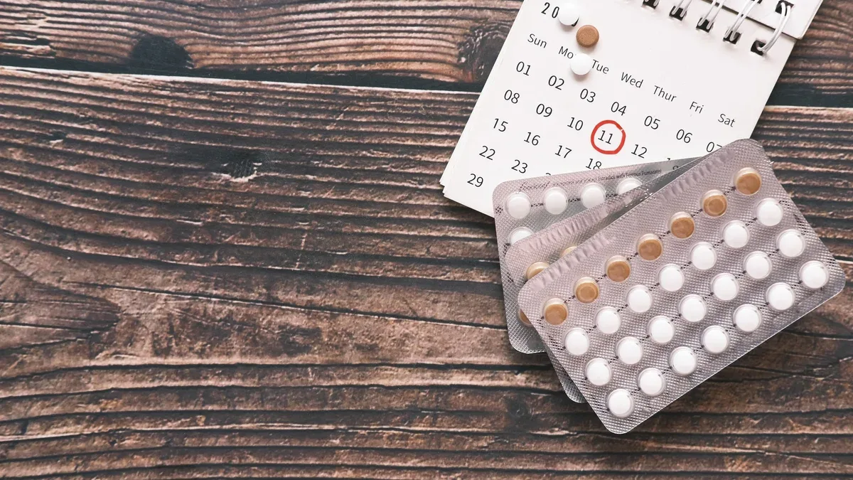 Vue de dessus des pilules contraceptives et un calendrier sur un bureau en bois