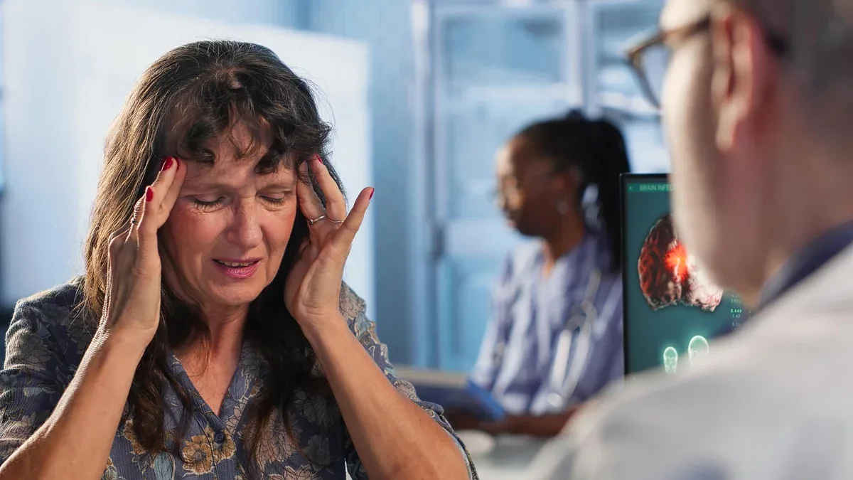 Femme âgée lors d'un examen médical souffrant d'un mal de tête douloureux et demandant conseil dans un établissement médical.