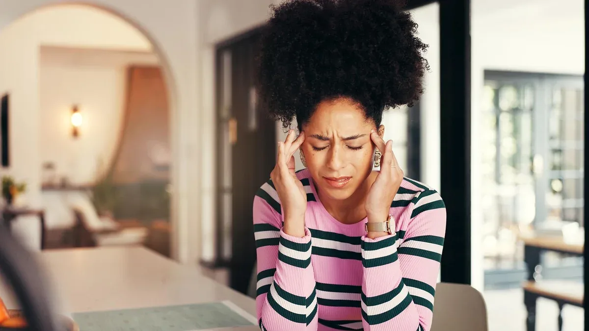 Femme frustrée, maux de tête à la maison, stressée par la surcharge de travail, la pression, la fatigue ou la tension. Freelance ou télétravailleuse avec des maux de tête ou des vertiges dus à une échéance de projet ou une erreur à la maison.