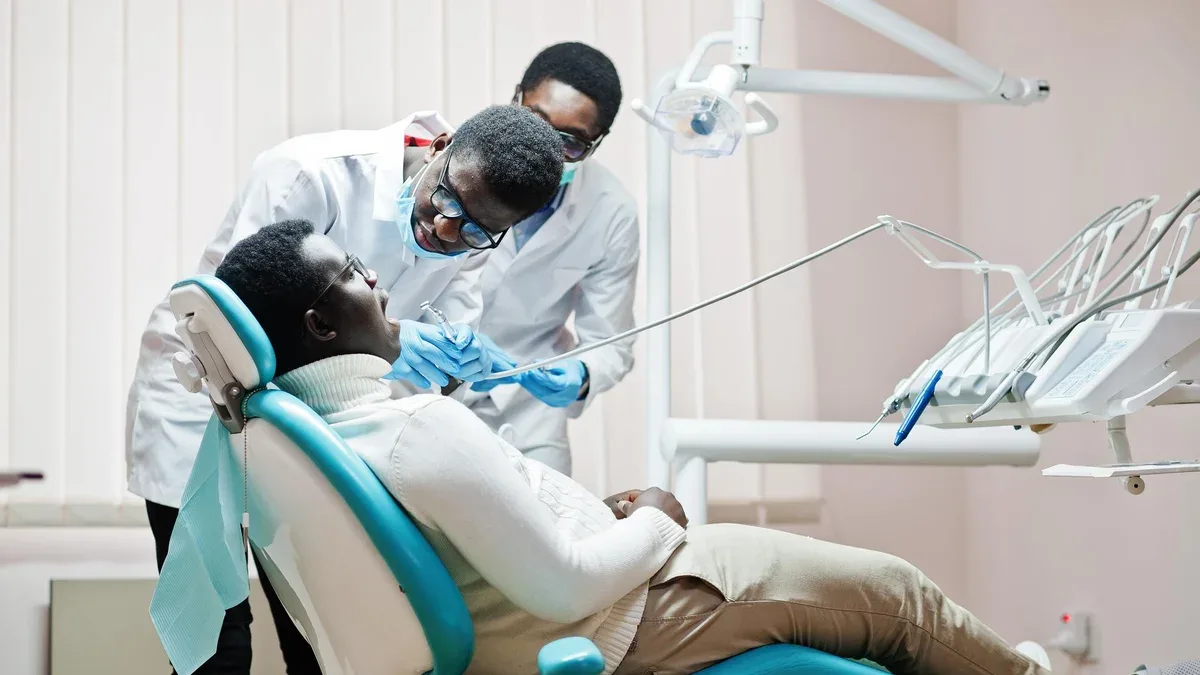 Patient afro-américain dans un fauteuil dentaire Cabinet de dentiste et concept de cabinet médical Dentiste professionnel aidant son patient à la dentisterie médicale Forage des dents du patient en clinique