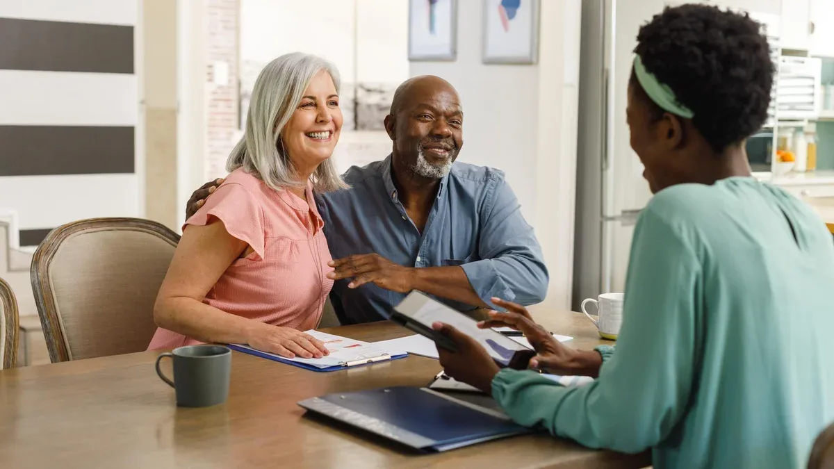 Heureux couple senior diversifié discutant avec une conseillère financière afro-américaine