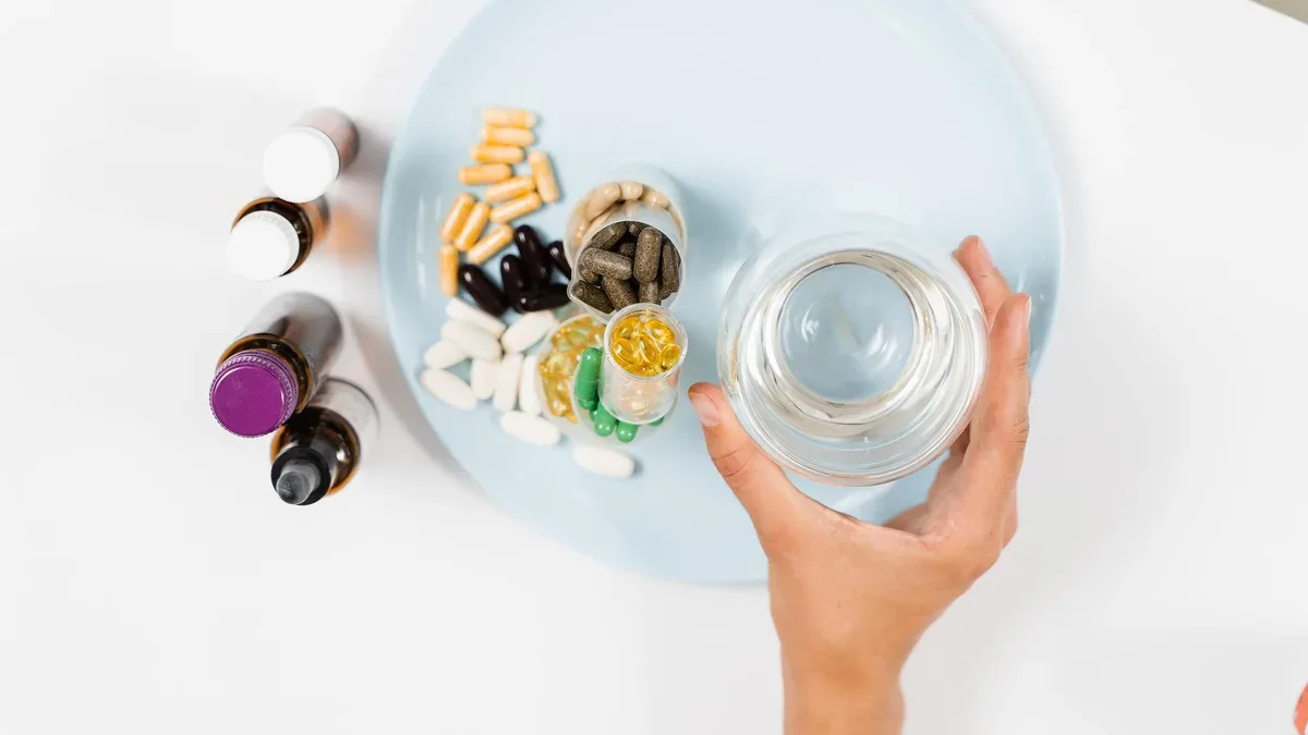 De nombreux compléments alimentaires comprimés et verre d'eau pour la prise quotidienne de pilules sur fond blanc Ensemble d'acides aminés mulvitamines minéraux et magnésium antistress mélatonine gros plan