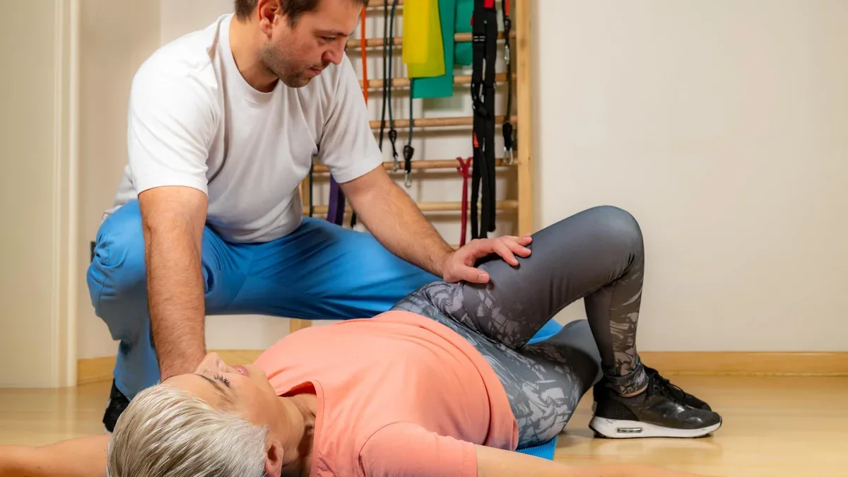 Instructeur de fitness masculin instruisant une femme mature faisant de l'exercice au gymnase