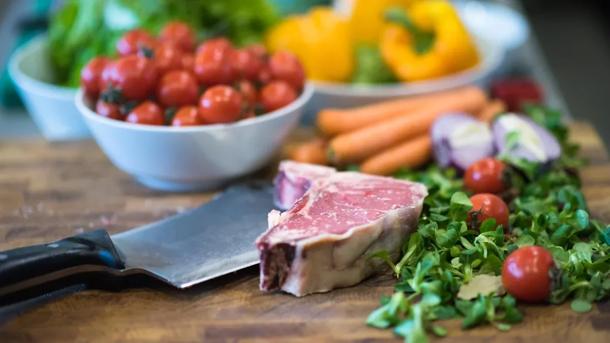 Tranche juteuse de steak cru avec des légumes autour sur une table en bois