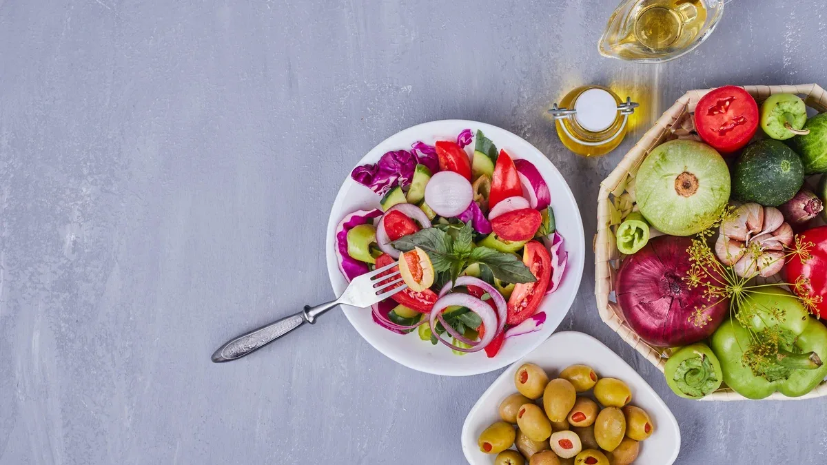 Salade légère aux légumes et herbes servie avec des olives vertes.