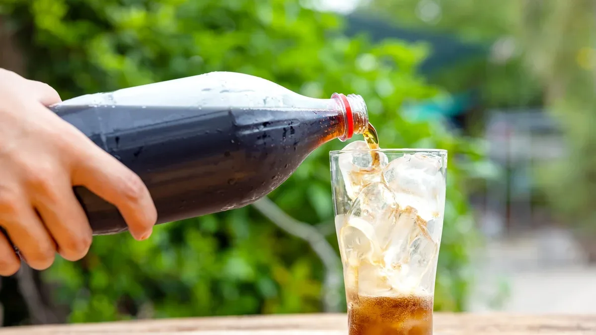 Verser la bouteille de verre en verre sur une table en bois dans le jardin
