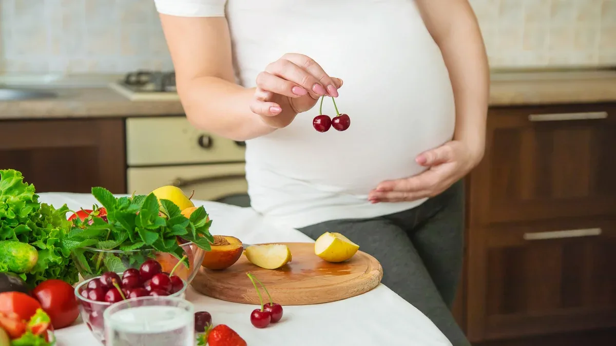 Une femme enceinte mange des légumes et des fruits